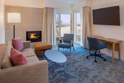 a living room with a couch and a desk and a fireplace at Hilton Garden Inn Dana Point Doheny Beach in Dana Point