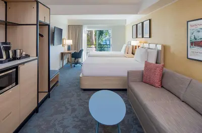 a hotel room with two beds and a couch at Hilton Garden Inn Dana Point Doheny Beach in Dana Point