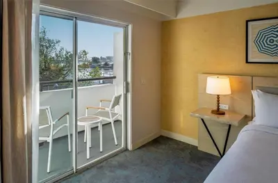 a bedroom with a balcony with a bed and a table and chairs at Hilton Garden Inn Dana Point Doheny Beach in Dana Point