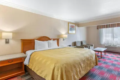 a hotel room with a large bed and a chair at Quality Inn & Suites Oceanside Near Camp Pendleton in Oceanside