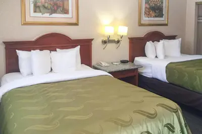 a hotel room with two beds with white and green sheets at Quality Inn & Suites Oceanside Near Camp Pendleton in Oceanside