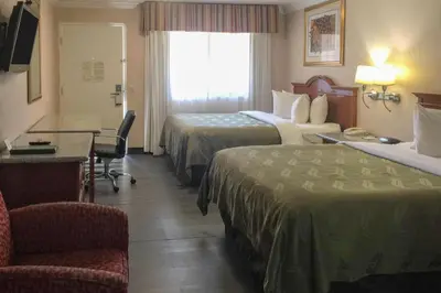 a hotel room with two beds and a desk at Quality Inn & Suites Oceanside Near Camp Pendleton in Oceanside