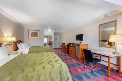 a hotel room with two beds and a desk at Quality Inn & Suites Oceanside Near Camp Pendleton in Oceanside