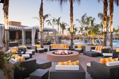a patio with chairs and a fire pit with palm trees at Marbrisa Carlsbad Resort in Carlsbad