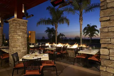 a restaurant with tables and chairs and palm trees at Marbrisa Carlsbad Resort in Carlsbad
