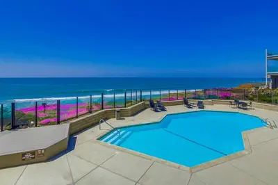 a swimming pool with the ocean in the background at Work Friendly Oceanfront SURF25 Condo in Solana Beach