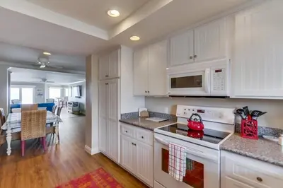 a kitchen with white cabinets and a red appliance at Work Friendly Oceanfront SURF25 Condo in Solana Beach