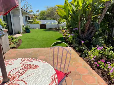 a table and chair on a patio with a garden at Kate Stanton Inn in Encinitas