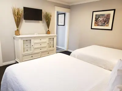a bedroom with two beds and a dresser with a tv at Coronado Inn in San Diego