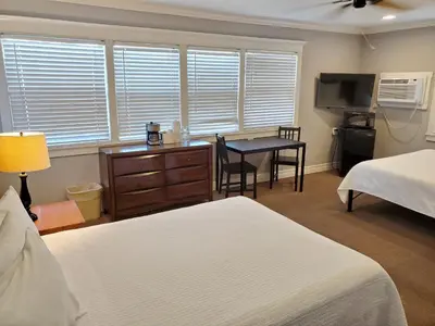 a bedroom with two beds and a desk with a table at Coronado Island Inn in San Diego