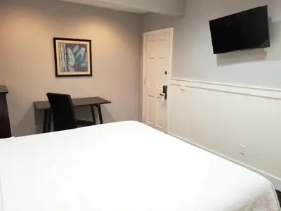 a bedroom with a bed and a desk and a television at Coronado Island Inn in San Diego