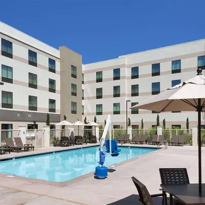 a pool in front of a hotel with chairs and an umbrella at Hampton Inn & Suites Murrieta Temecula in Murrieta