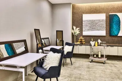 a waiting room with chairs and tables and paintings at AC Hotel by Marriott Irvine in Irvine