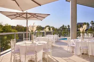 a row of tables with white chairs and an umbrella at AC Hotel by Marriott Irvine in Irvine