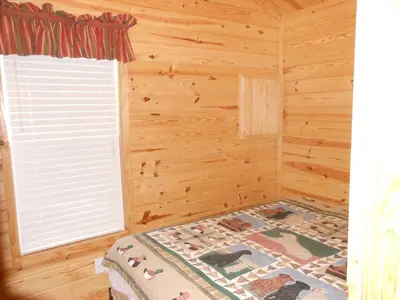 a bedroom with a bed in a wooden room with a window at Oakzanita Springs Camping Resort Cabin 1 in Descanso