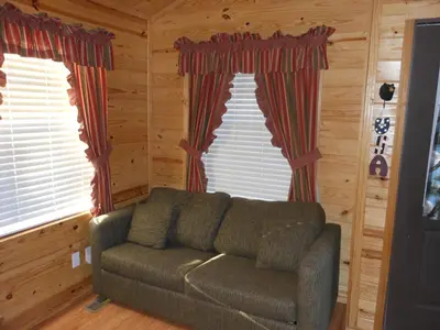 a living room with a couch in front of two windows at Oakzanita Springs Camping Resort Cabin 1 in Descanso