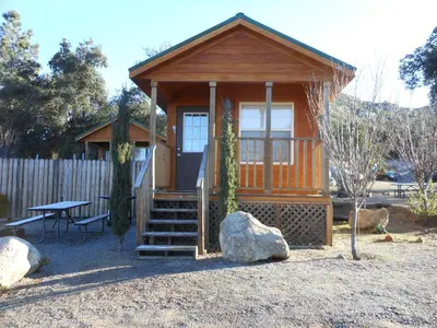 a small wooden cabin with a bench and a table at Oakzanita Springs Camping Resort Cabin 2 in Descanso