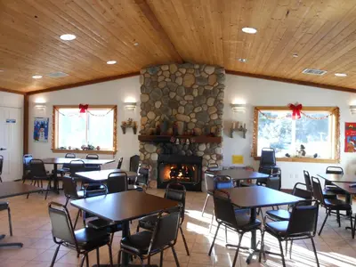 a restaurant with tables and chairs and a fireplace at Oakzanita Springs Camping Resort Cabin 2 in Descanso