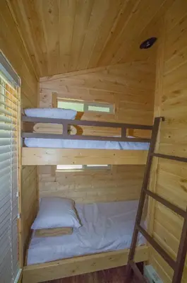 two bunk beds in a wooden cabin with a ladder at Oakzanita Springs Camping Resort Cottage 4 in Descanso