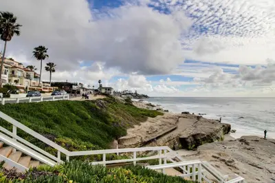 a beach with a white fence and the ocean at La Jolla Cottage in San Diego