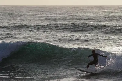 a man riding a wave on a surfboard in the ocean at La Jolla Cottage in San Diego