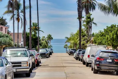 a row of cars parked on a street with palm trees at La Jolla Cottage in San Diego