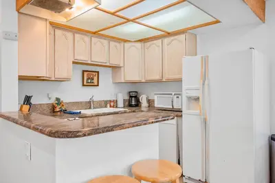 a kitchen with wooden cabinets and a white refrigerator at Mike's Place at the Beach in San Diego