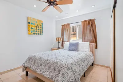 a bedroom with a bed and a ceiling fan at Mike's Place at the Beach in San Diego
