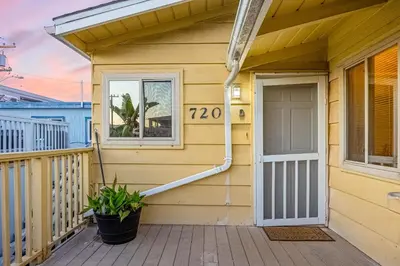 a yellow house with a porch with a door at Mimi's & Nana's Beach House in San Diego