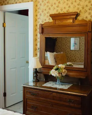 a bedroom with a mirror and a table with a vase of flowers at Julian Gold Rush Hotel in Julian