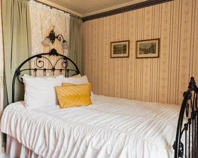 a bedroom with a large bed with white sheets at Julian Gold Rush Hotel in Julian