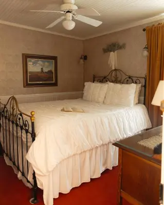 a bedroom with a large white bed with a fan at Julian Gold Rush Hotel in Julian