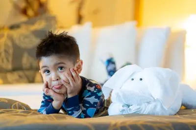 a young boy laying on a bed with his hand over his face at The Dana on Mission Bay in San Diego