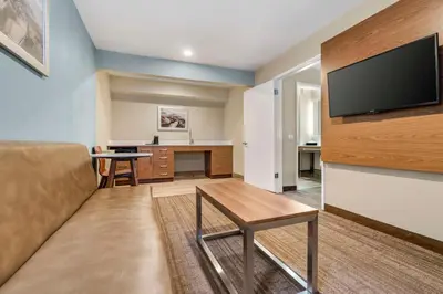 a living room with a couch and a flat screen tv at Best Western Carlsbad by the Sea in Carlsbad