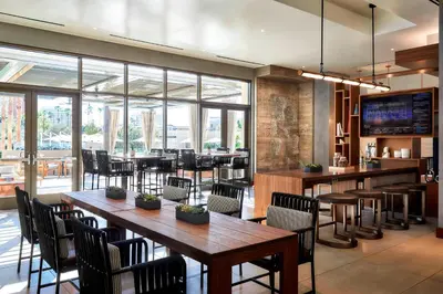 a restaurant with wooden tables and chairs and windows at Marriott Irvine Spectrum in Irvine