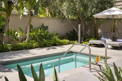 a swimming pool in a garden with an umbrella at Marriott Irvine Spectrum in Irvine