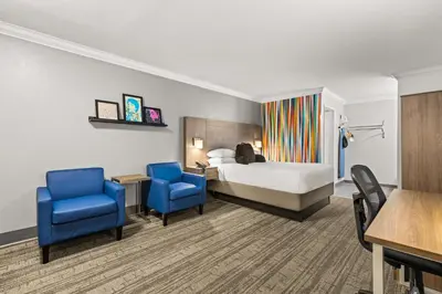 a hotel room with a bed and two blue chairs at Signature Temecula in Temecula