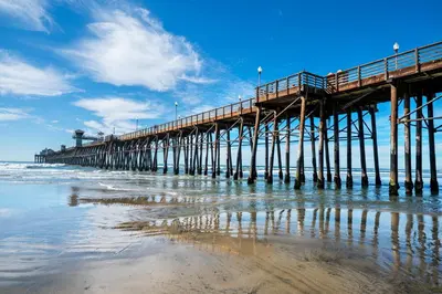 a pier on the beach next to the ocean at Oceanside Rocks Family Vacation Home in Oceanside