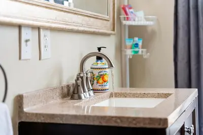 a bathroom sink with a faucet and a mirror at Oceanside Rocks Family Vacation Home in Oceanside