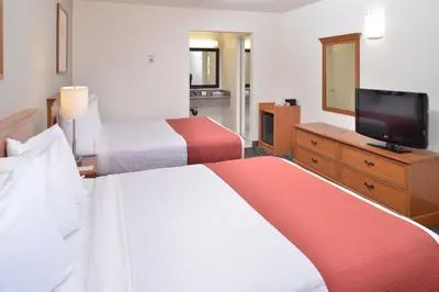 a hotel room with two beds and a flat screen tv at Pleasant Inn in San Diego