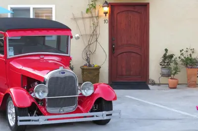 an old red car parked in front of a door at Leucadia Beach Inn in Encinitas