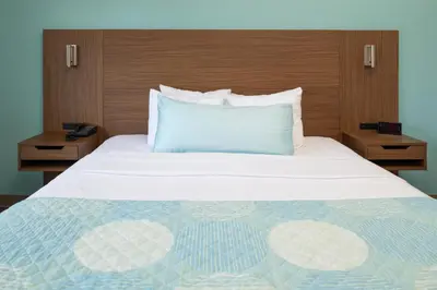 a bedroom with a large bed with a blue pillow at Brisa Pacific Hotel Encinitas in Encinitas