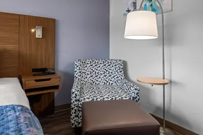 a bedroom with a chair and a table and a lamp at Brisa Pacific Hotel Encinitas in Encinitas