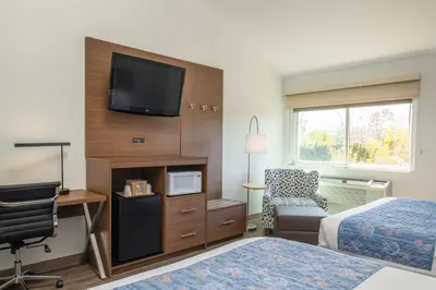 a hotel room with two beds and a television on a wall at Brisa Pacific Hotel Encinitas in Encinitas