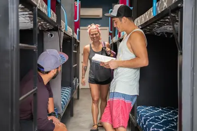 a man and a woman standing in a room with bunk beds at California Dreams Hostel - Pacific Beach in San Diego