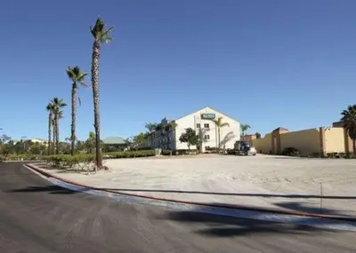 an empty street with palm trees and a house at Quality Suites San Diego Otay Mesa in Otay Mesa
