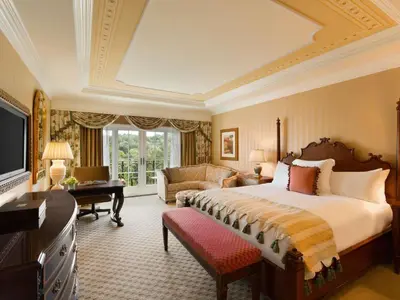 a bedroom with a bed and a couch and a television at Fairmont Grand Del Mar in San Diego