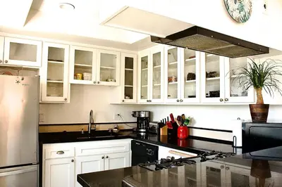 a kitchen with white cabinets and a black counter top at Sweet Beach Duplex in Newport Beach