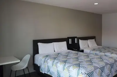 a bedroom with two beds and a table and a chair at Motel 6-San Diego, CA - Southbay in Chula Vista