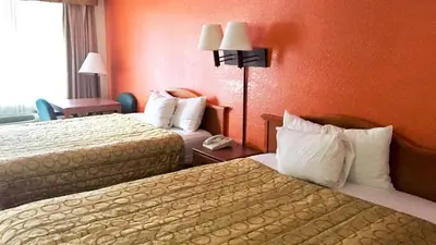 two beds in a hotel room with orange walls at Motel 6-San Diego, CA - Southbay in Chula Vista
